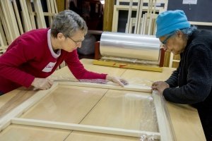 Volunteers assemble window inserts at a community build